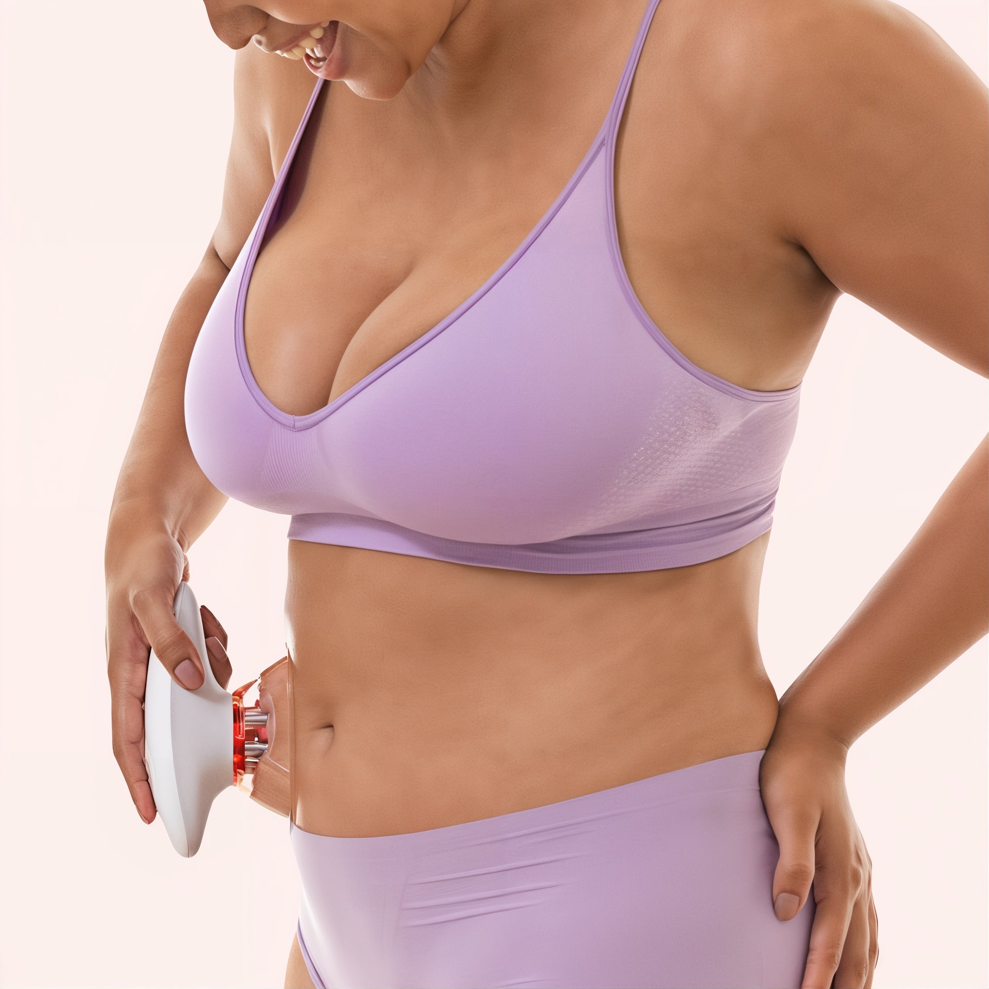 A woman in a lavender sports bra and matching high-waisted shorts is using a MiaBody shapper device on her abdomen. She is smiling and focused, demonstrating the device's application for body contouring and skincare.